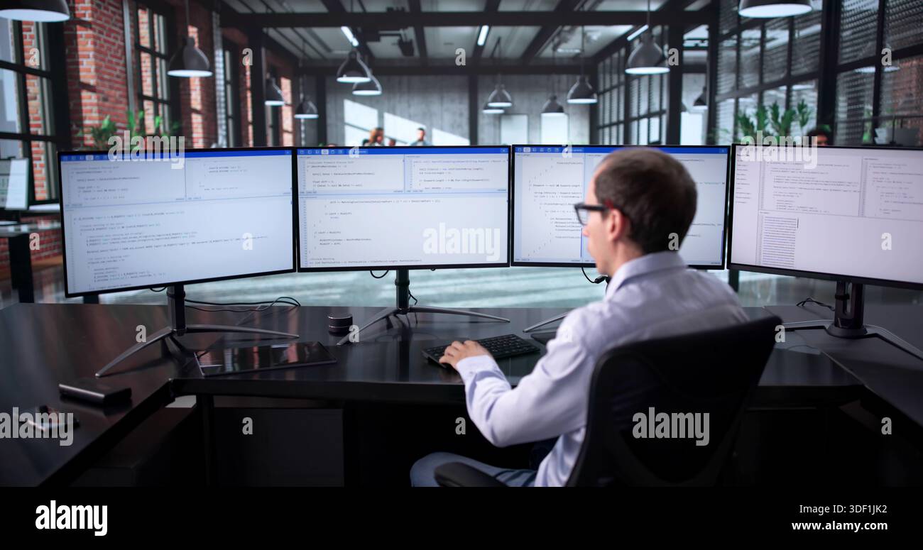 Technisch Versierter Mann, Der Mehrere Bildschirme In Geschäftiger Büroumgebung Jongliert Stockfoto