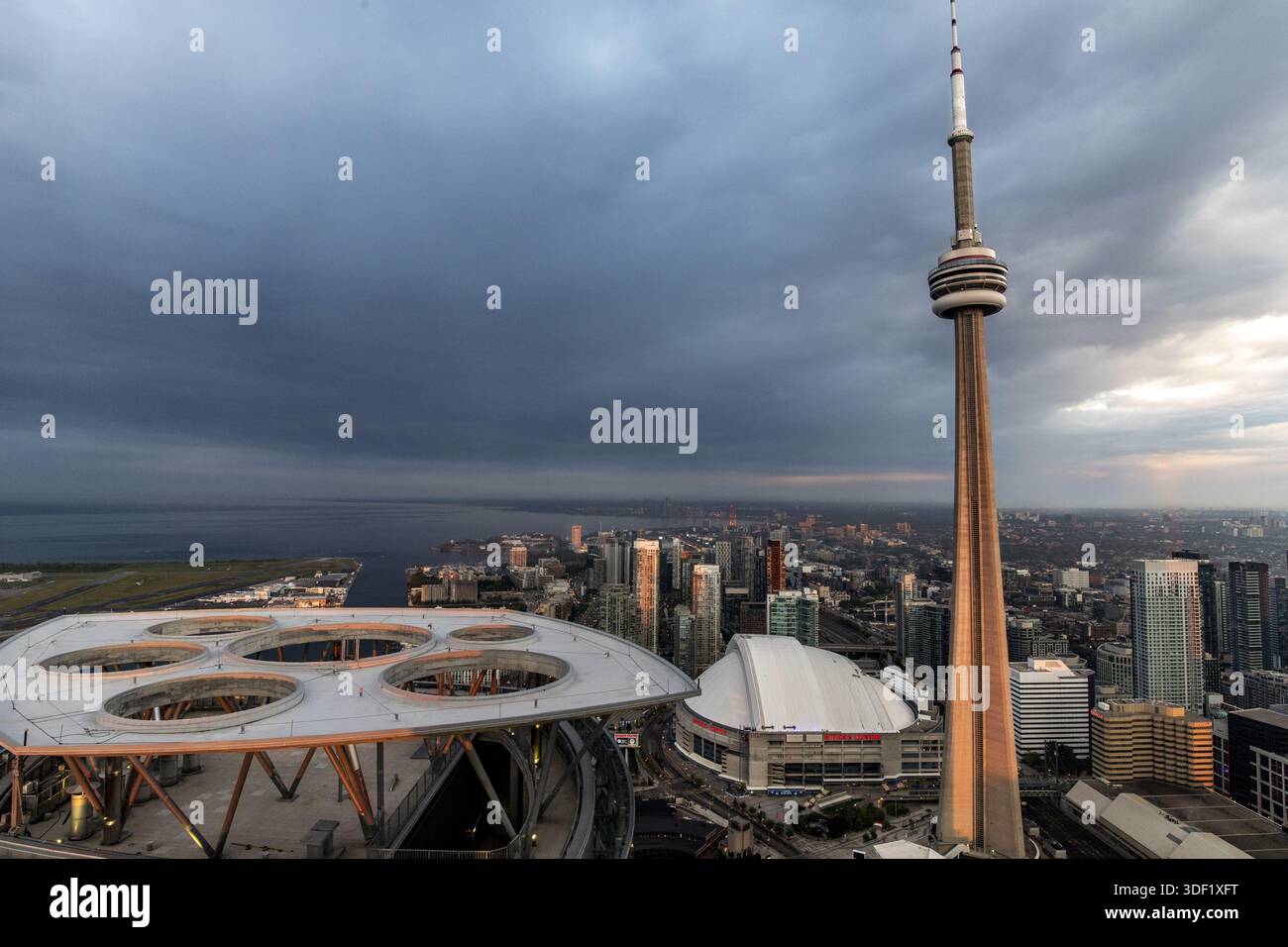 Blick auf den CN Tower, der sich durch die Skyline zieht, hoch in einer weitläufigen Stadtlandschaft unter einem dramatischen Himmel steht, ein Stadion sichtbar, Toronto, Onta Stockfoto