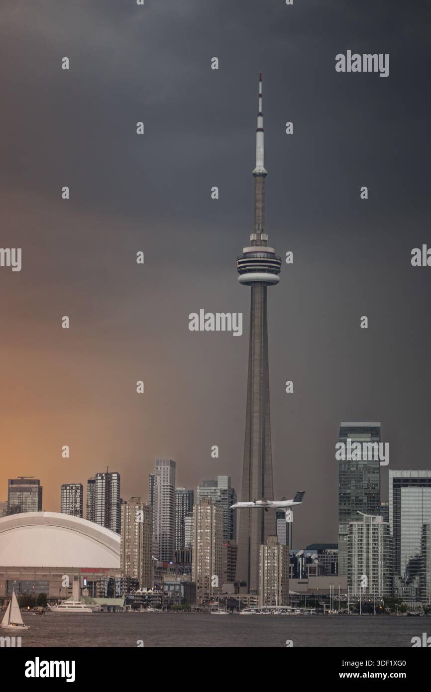 Blick auf eine dramatische Skyline mit dem CN Tower, der durch den stürmischen Himmel mit einem Segelboot auf dem Wasser gleitet, Toronto, Ontario, Kanada. Stockfoto