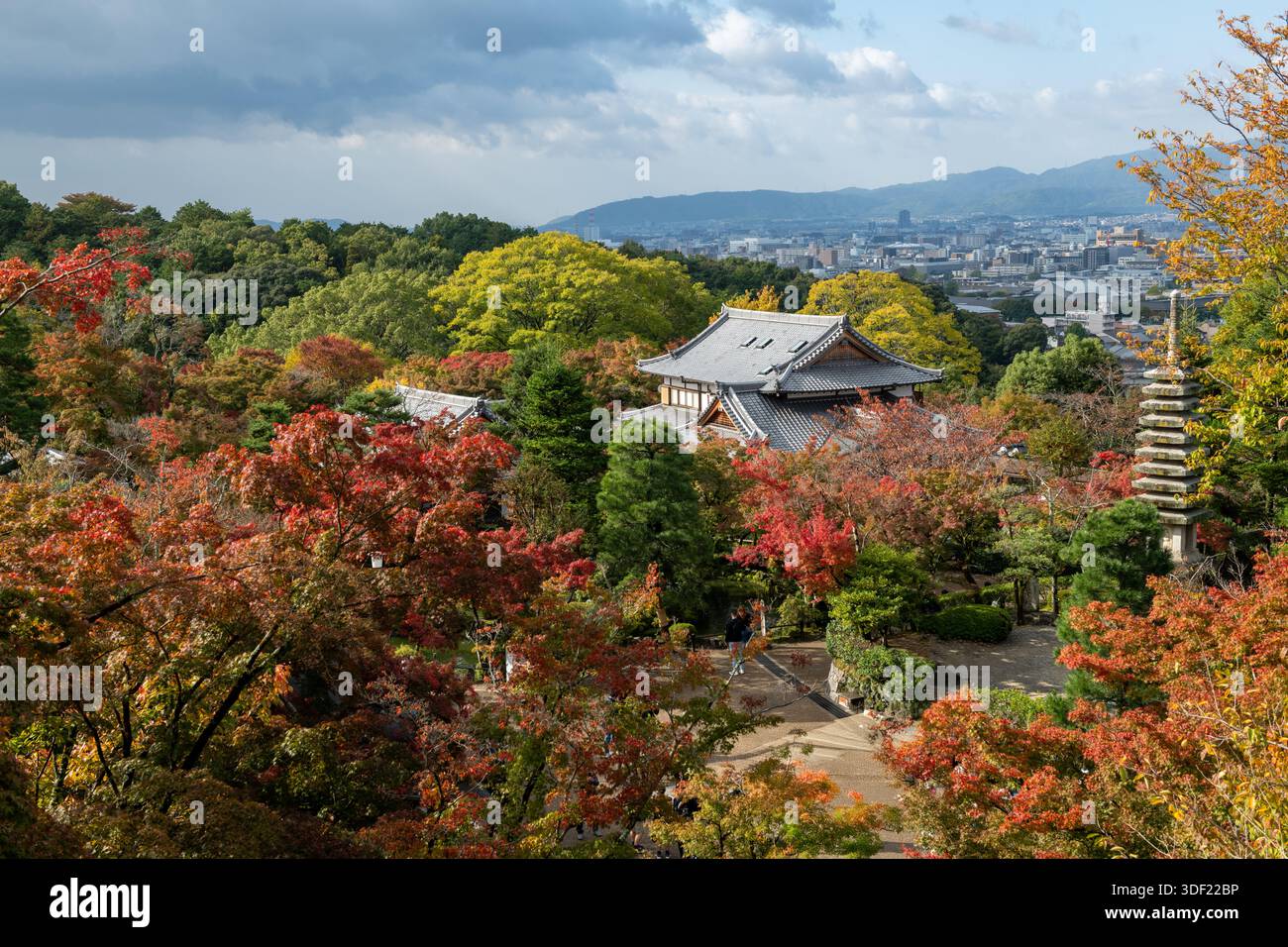 Blick auf das lebhafte Herbstlaub rund um traditionelle Tempel und Pagoden, im Kontrast zur fernen modernen Stadtlandschaft, Kyoto, Kyoto, Japan. Stockfoto