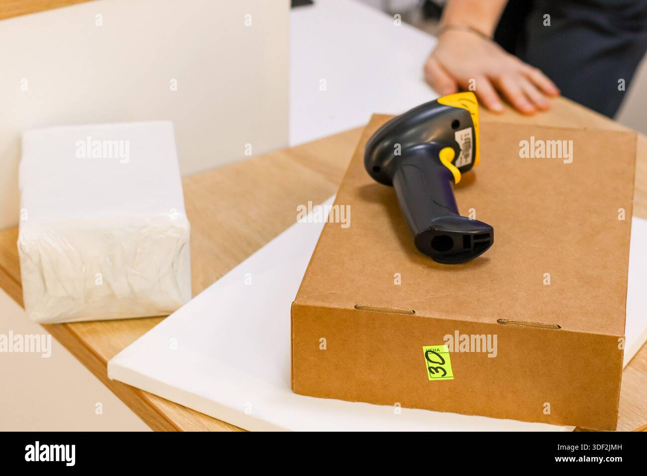 Nahaufnahme von Versandkarton, Barcode-Lesegerät und Verpackungsmaterial auf dem Schreibtisch Stockfoto