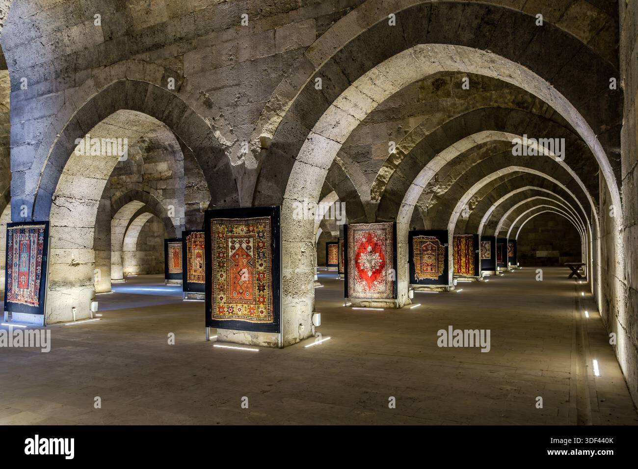 Das Sultan Hanı Caravanserai präsentiert einen roten Teppich mit einem runden Medaillonmuster als Blickfang zwischen den Reihen von Steinbögen in seiner gewölbten Winterhalle. Sultan Alaeddin Keykubad I ließ das Caravanserai 1229 in Sultanhanı, Zentralanatolien, errichten. Mit einer Fläche von etwa 4.900 Quadratmetern ist es das größte seldschukische Caravanserai in Anatolien, einst eine Station auf der historischen Handelsroute zwischen Konya und Aksaray, Türkei. Stockfoto