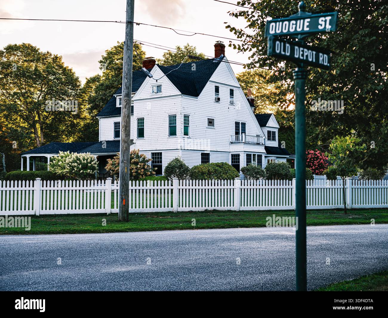 Ein schindelförmiges Küstenhaus mit weißem Pflückenzaun an einer ruhigen Straßenecke in Quogue, Long Island, New York. Stockfoto