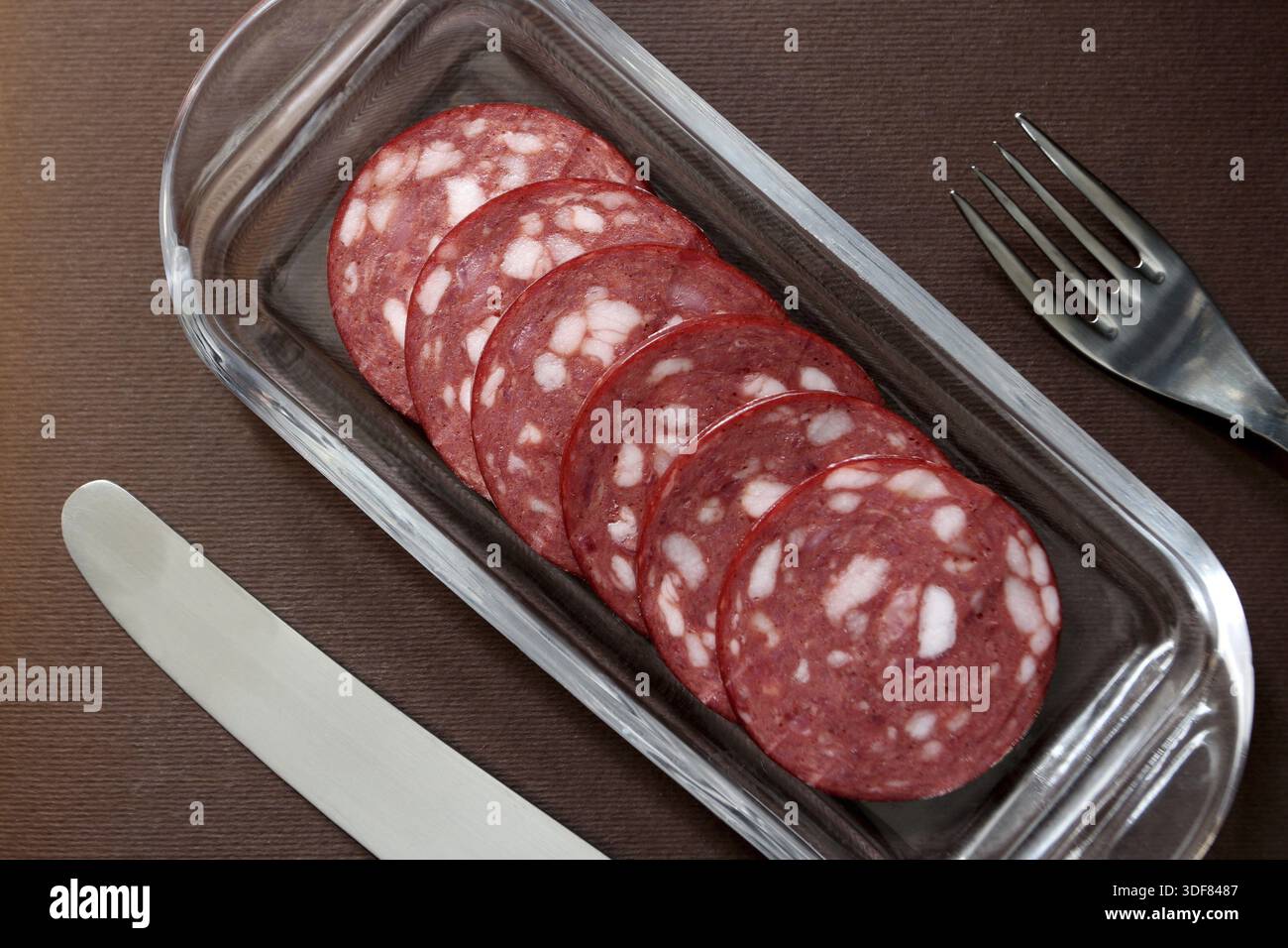 Salami in Scheiben auf einem Teller mit Besteck Stockfoto
