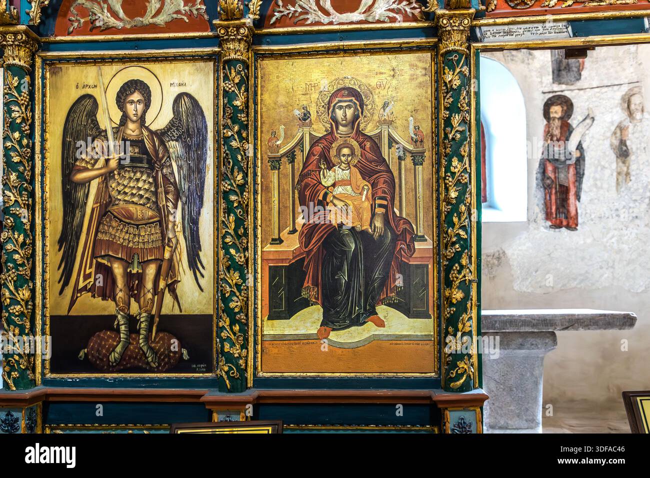 Zwei Ikonen auf der Ikonostase der Hagia Eleni Kirche in Sille bei Konya, Türkei, zeigen den gepanzerten Erzengel Michael und die thronende Mutter Gottes mit Kind. Durch eine offene Tür erstreckt sich der Blick in einen mit Fresken verzierten Seitenraum der Kirche. Stockfoto