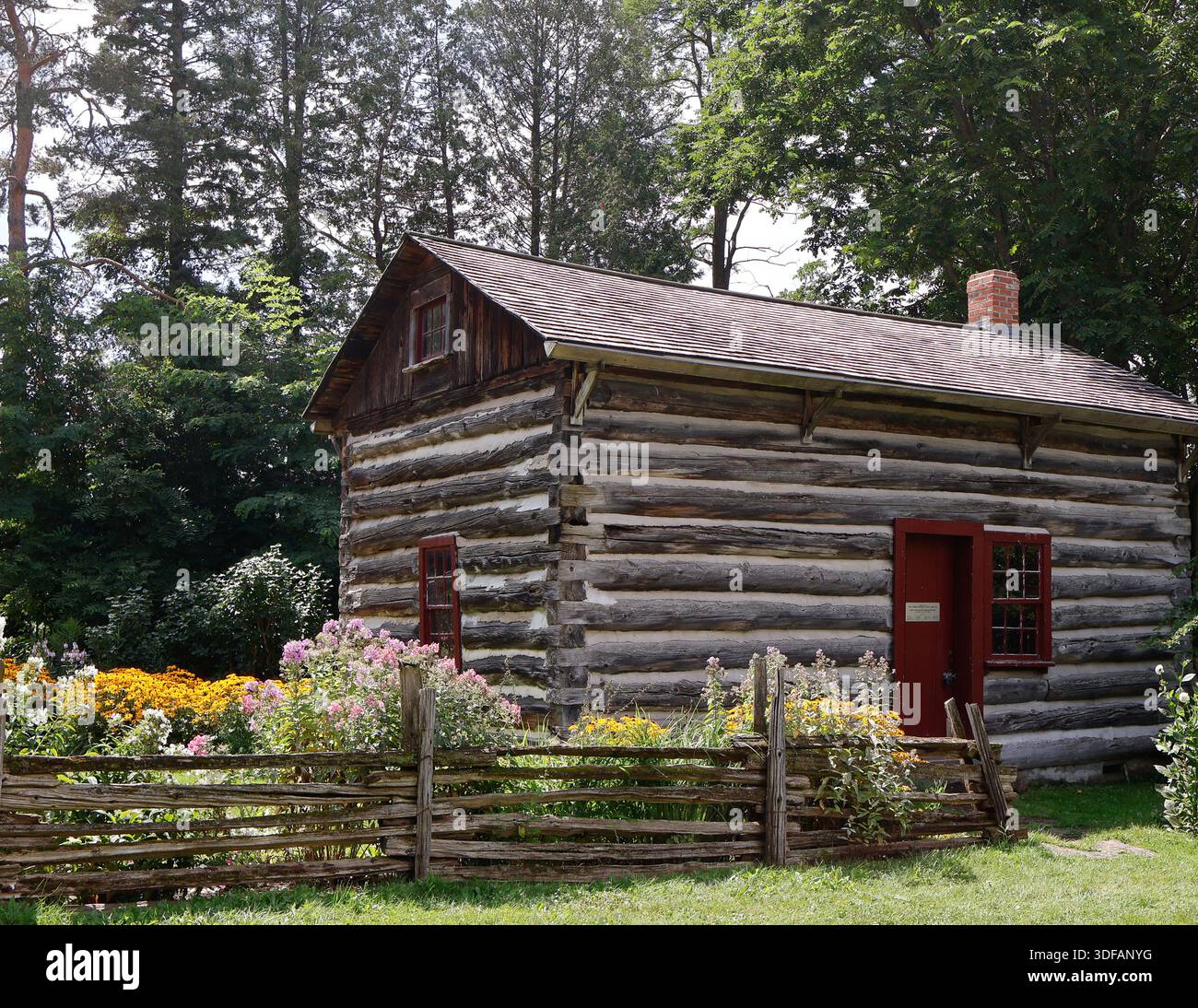 Eine Blockhütte umgeben von Gärten und einem alten hölzernen Bauernzaun Stockfoto