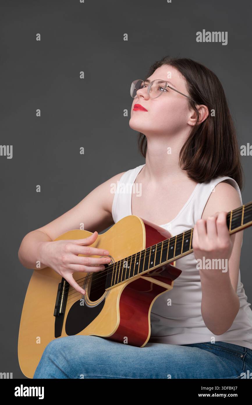 Ein Gitarrist mit ruhiger Geselligkeit spielt während der Performance Akustikgitarre und demonstriert ein tiefes Maß an Engagement für kreativen Ausdruck. Europea Stockfoto