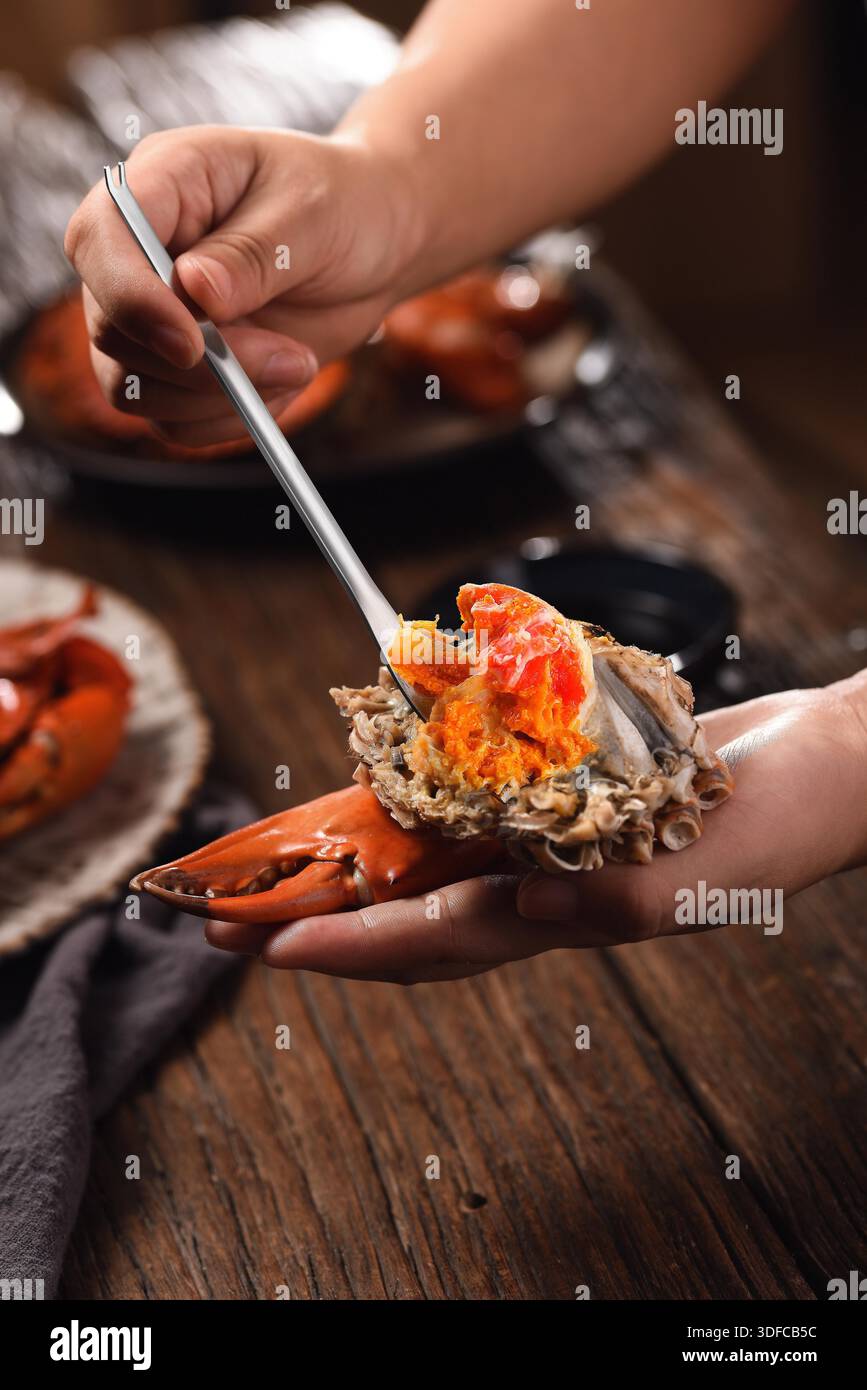 Professionelles Meeresfrüchte-Werkzeugset mit Nussknacker-Schere und Gabeln zum Essen von Krabben auf Holztablett, Blick von oben auf Menschen, die gedämpfte Schlammkrabben essen Stockfoto