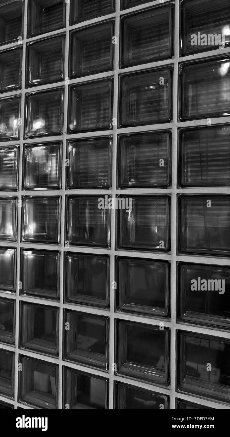 Elegante dunkle Glasblockwand mit Gittermuster und dezenten Reflexen. Die raffinierte architektonische Mattglasziegelstruktur ist perfekt für die Moderne Stockfoto