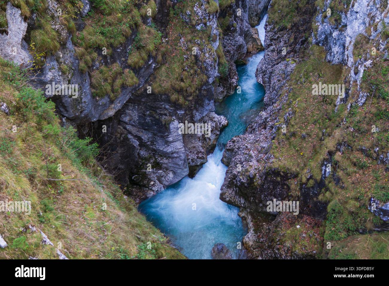 Blick von oben auf einen türkisfarbenen Tauchpool, der von einem Bergbach in einer engen felsigen Schlucht gebildet wird. Stockfoto