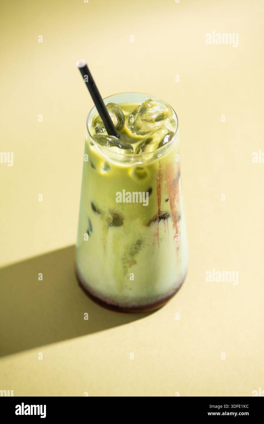 Eisgetränk Himbeer Matcha serviert in einem klaren Glas mit Eis. Farbenfrohe mehrschichtige Getränke, fotografiert auf einem sauberen, minimalistischen Studiohintergrund. Stockfoto