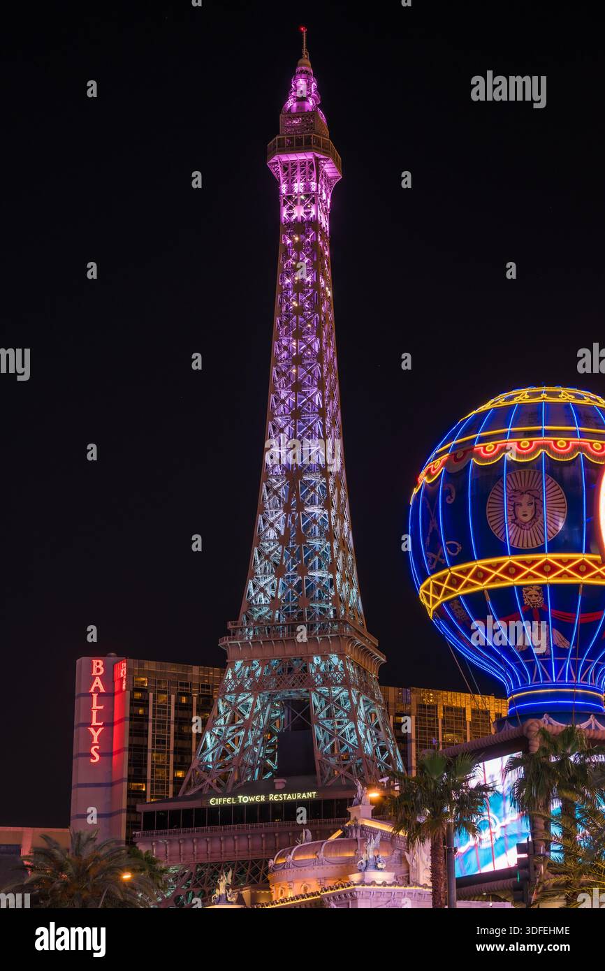 Der Blick auf den Nachbau des Eiffelturms erhebt sich am Nachthimmel und leuchtet mit rosa und blauen Lichtern neben einer hellblauen Heißluftballon-Attraktion, Las Vegas Stockfoto