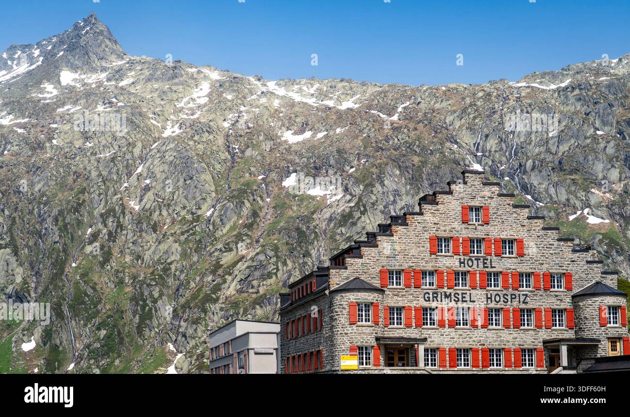 Historisches Hotel mit roten Fensterläden vor Bergkulisse. Stockfoto