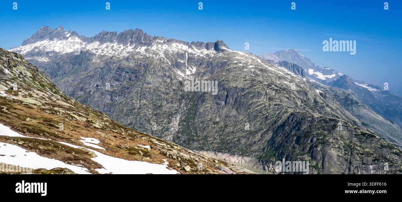 Panoramablick auf schneebedeckte Berge unter einem klaren blauen Himmel. Stockfoto