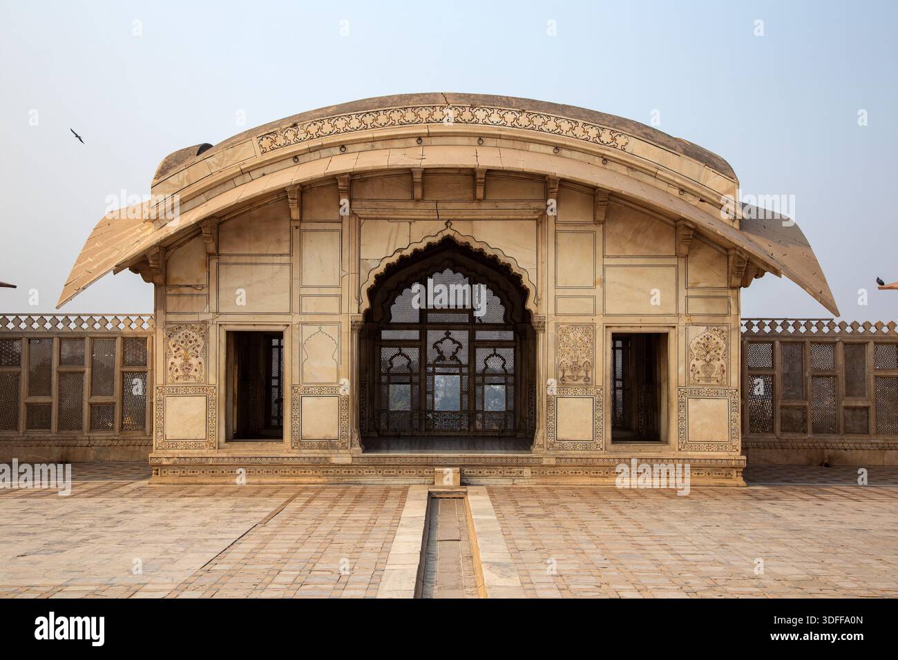 Der Blick auf eine atemberaubende weiße Marmorstruktur mit komplizierten Schnitzereien steht majestätisch unter dem weichen Himmel und verkörpert architektonische Pracht, für die Lahore steht Stockfoto