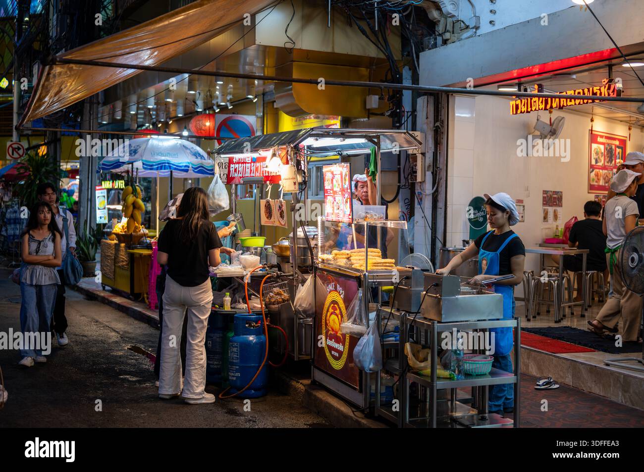 Bangkok, Thailand - 11.11.2025: Street Food Stände in Bangkok bei Nacht, glühend vor warmen Lichtern, während Köche frische Mahlzeiten für vorbeiziehende Menschen zubereiten, captain Stockfoto