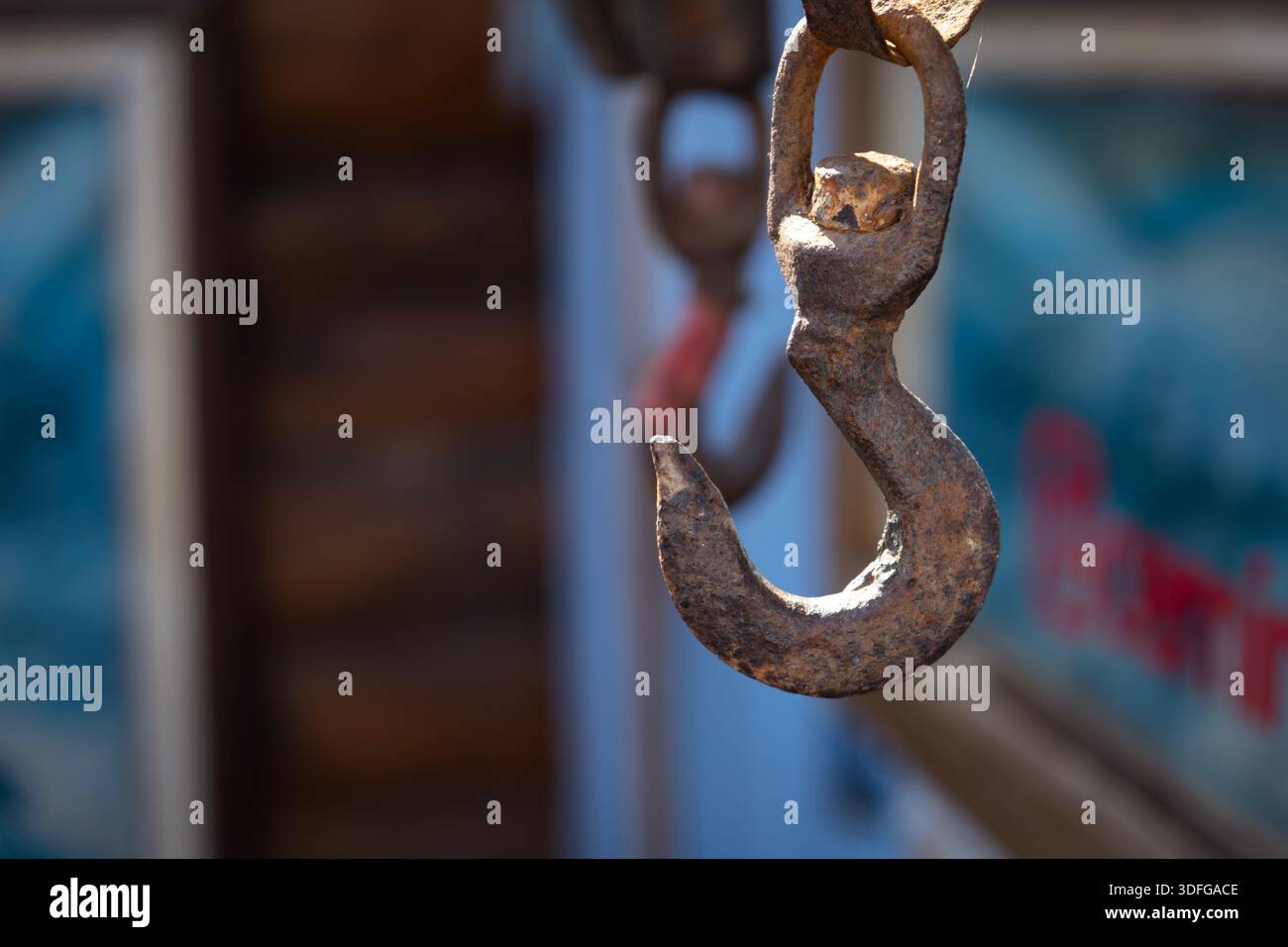 Rostiger Industriehaken, der an der Kette hängt, zeigt Korrosion, Festigkeit und industrielle Widerstandsfähigkeit Stockfoto