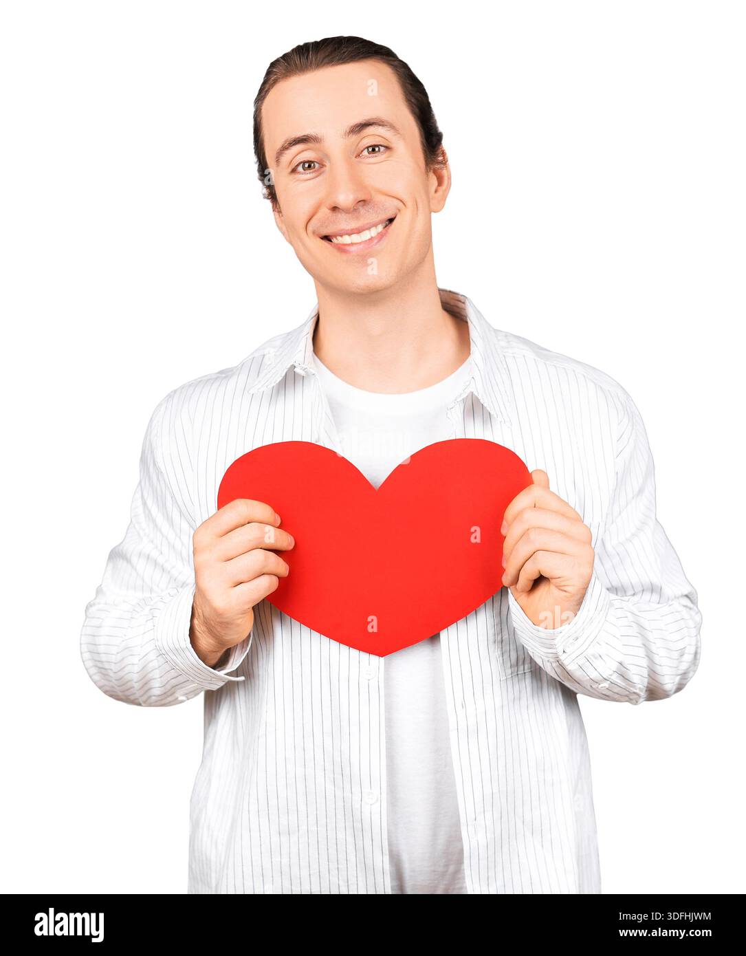 Ein lächelnder, gutaussehender Mann, der ein rotes Herz in der Nähe seiner Brust hält. Porträt eines glücklichen Romantikers für Valentinstag-Konzept isoliert auf weißem Hintergrund. Hallo Stockfoto