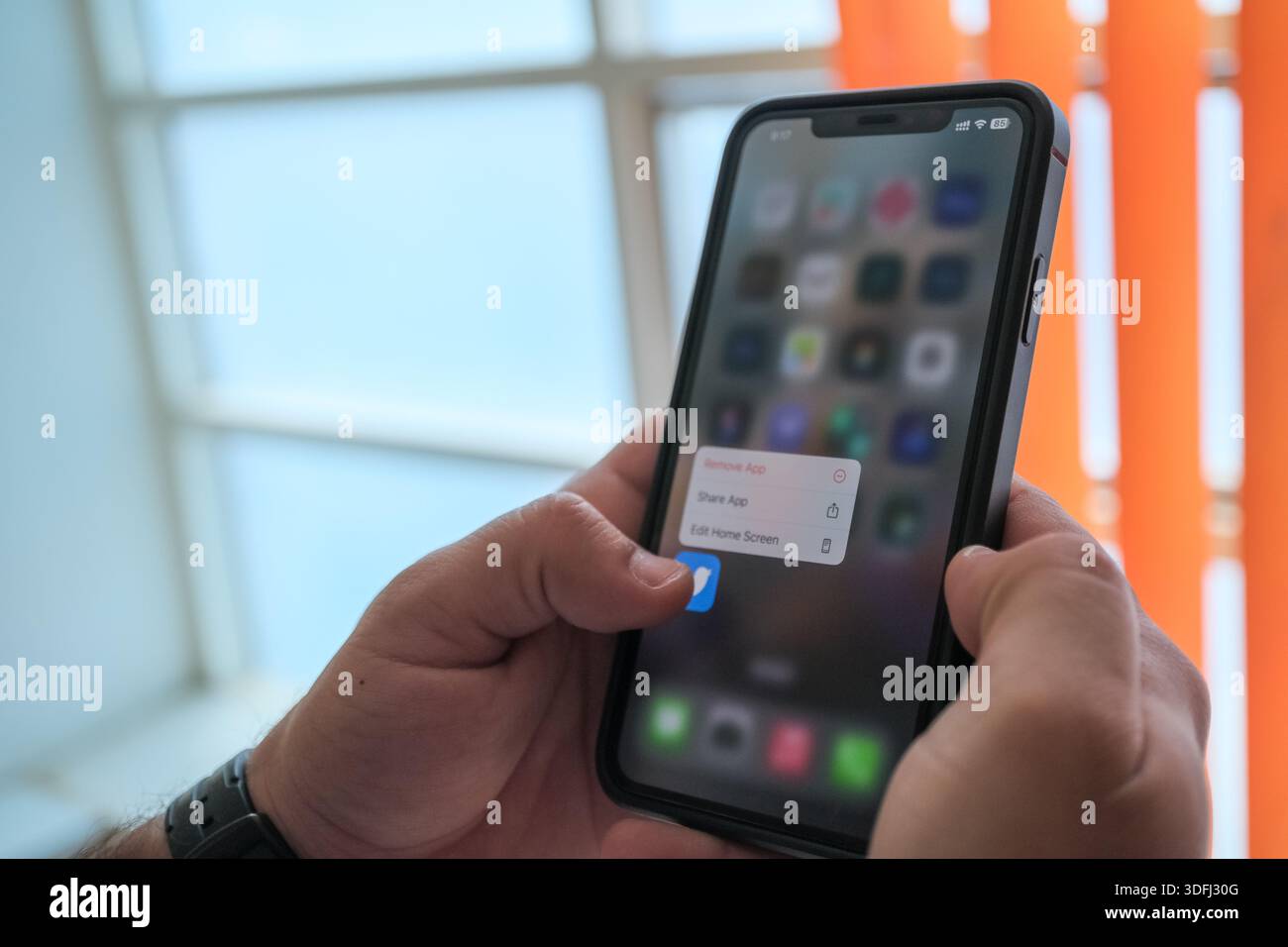 Eine Person, die ein Smartphone mit einem sichtbaren App-Menü auf dem Bildschirm hält, das die Interaktion mit dem Gerät zeigt Stockfoto