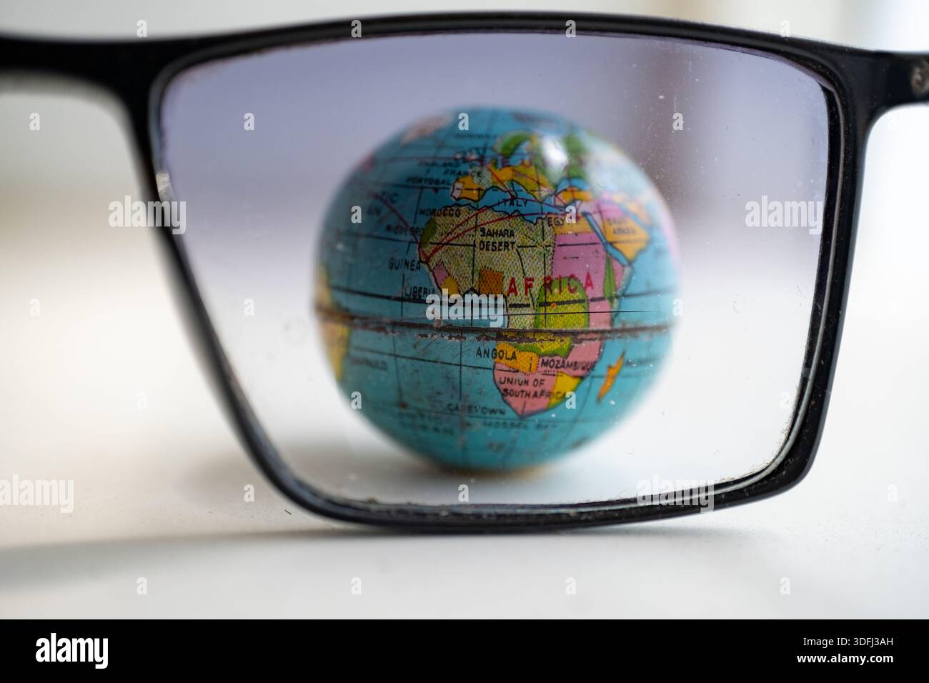 Eine Nahaufnahme eines Globus, der Afrika darstellt, durch eine Brille gesehen, die die Weltkarte und geografische Besonderheiten hervorhebt Stockfoto