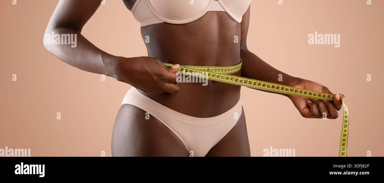 Messen der Taillengröße in einer Studio-Einstellung während einer Fitness-Beurteilung Stockfoto