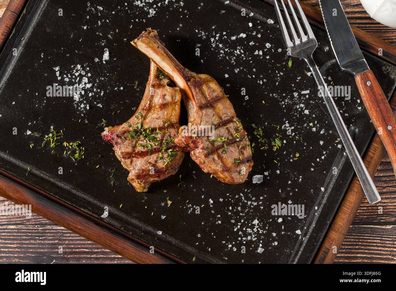 Gegrillte Lammkoteletts auf schwarzem Steinteller Stockfoto
