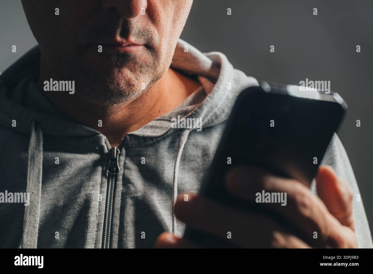 Nahaufnahme eines Gelegenheitsmannes mit Smartphone, nur das untere Gesicht mit Mund und Kinn im Fokus und ein Teil des Telefons ist im Vordergrund verschwommen. Selektiver Fokus. Stockfoto