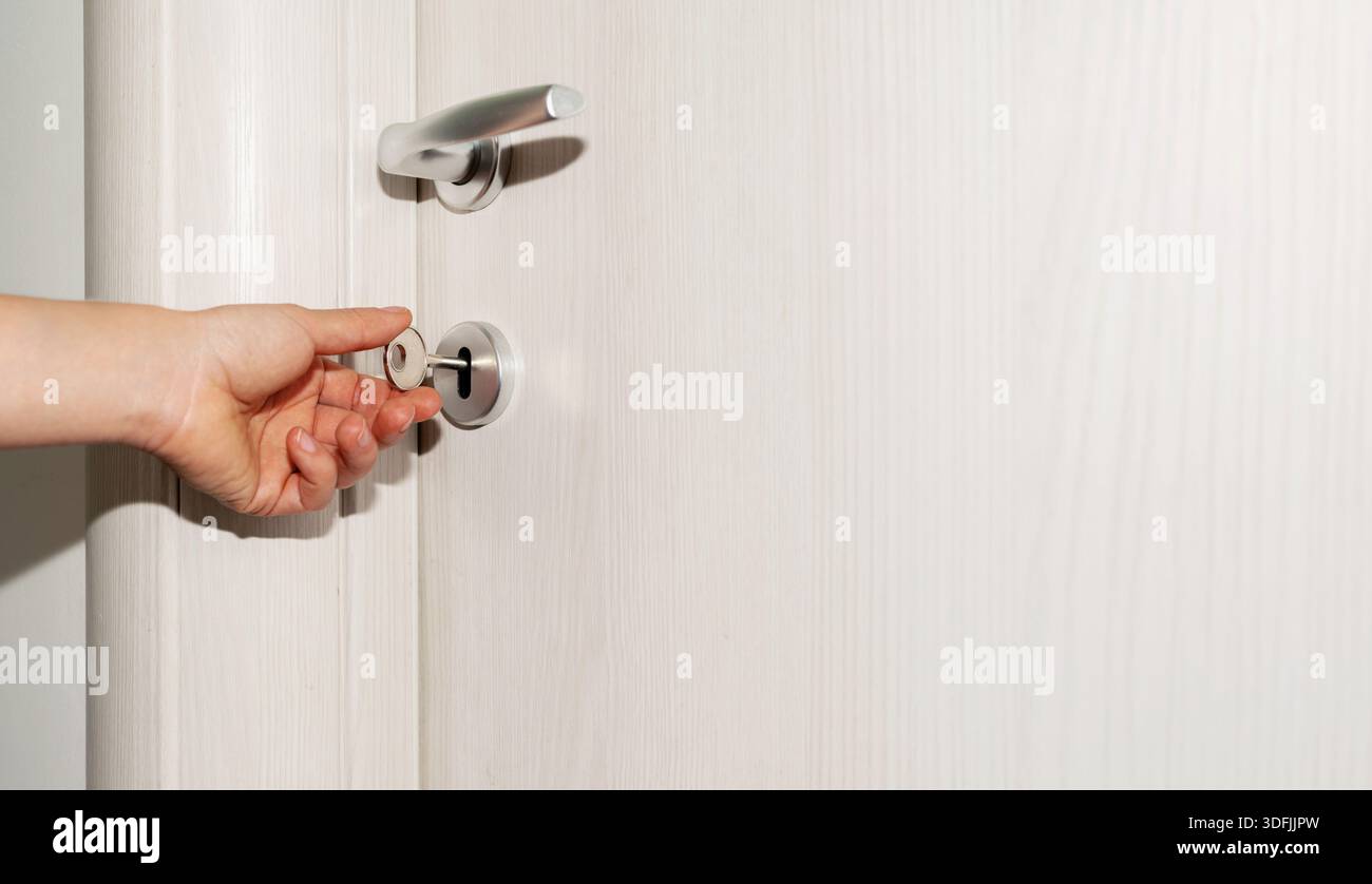 Die weibliche Hand öffnet die Tür mit der Schlüsselnaht. Stockfoto