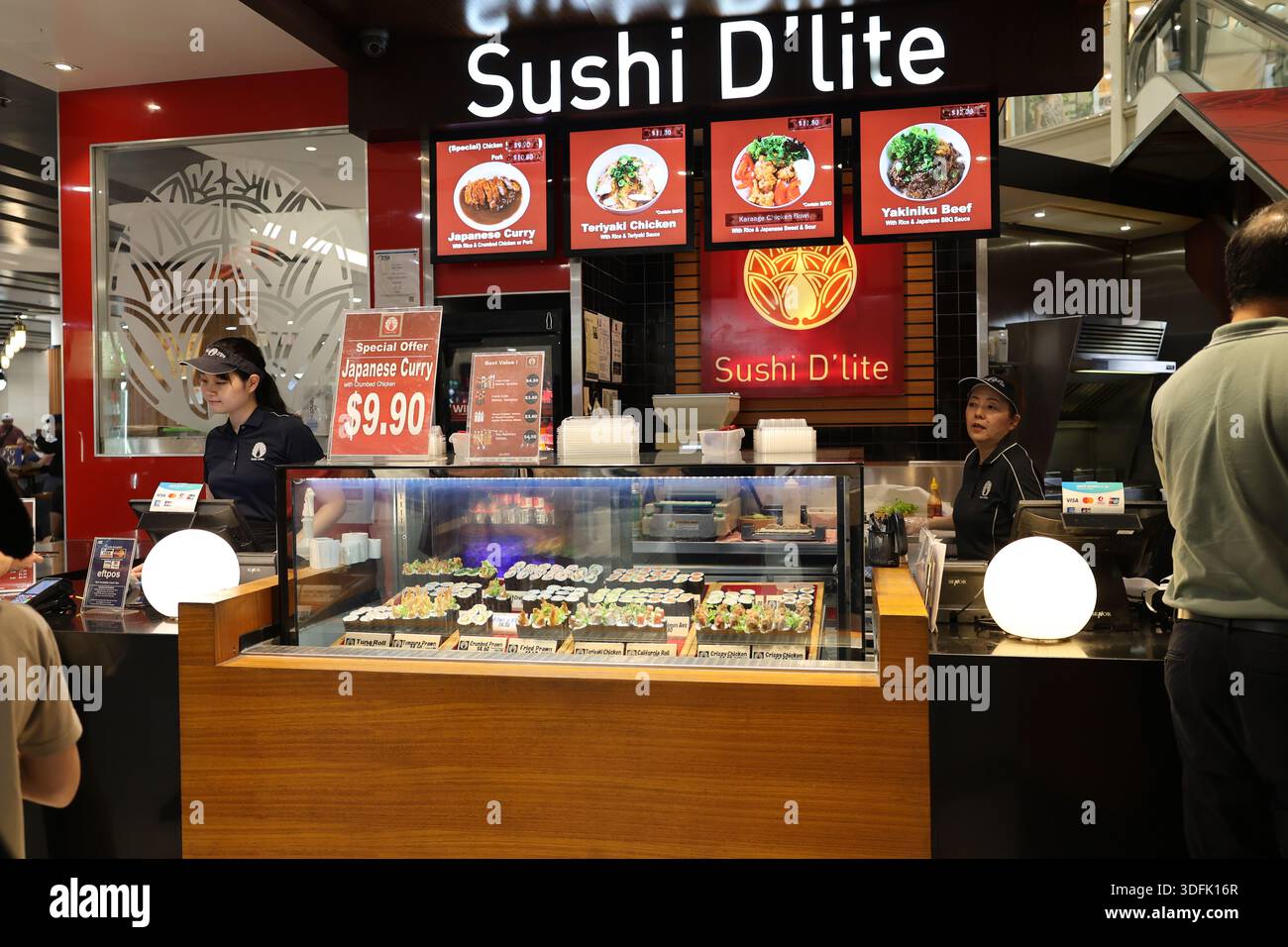 Zwei Mitarbeiter in Uniform servieren Kunden in einer Sushi-Bar in der Uptown Mall, Brisbane, Queensland, Australien, Januar 2026. Stockfoto