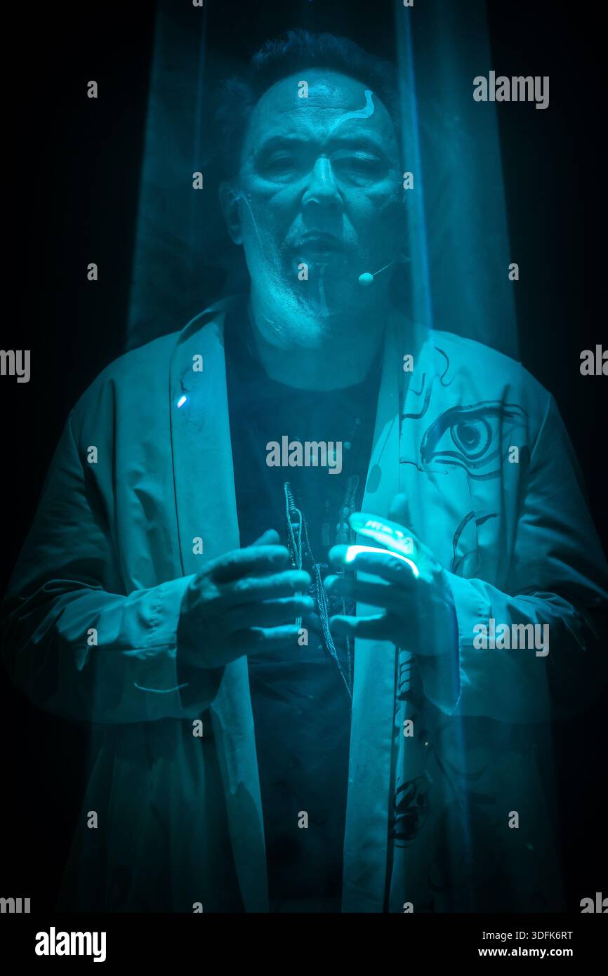 Ein dramatisches Sci-fi-Porträt, das einen Mann zeigt, der in einer glühend blauen Kammer eingetaucht ist und eine rituelle Interaktion mit fortschrittlicher Technologie durchführt. Stockfoto