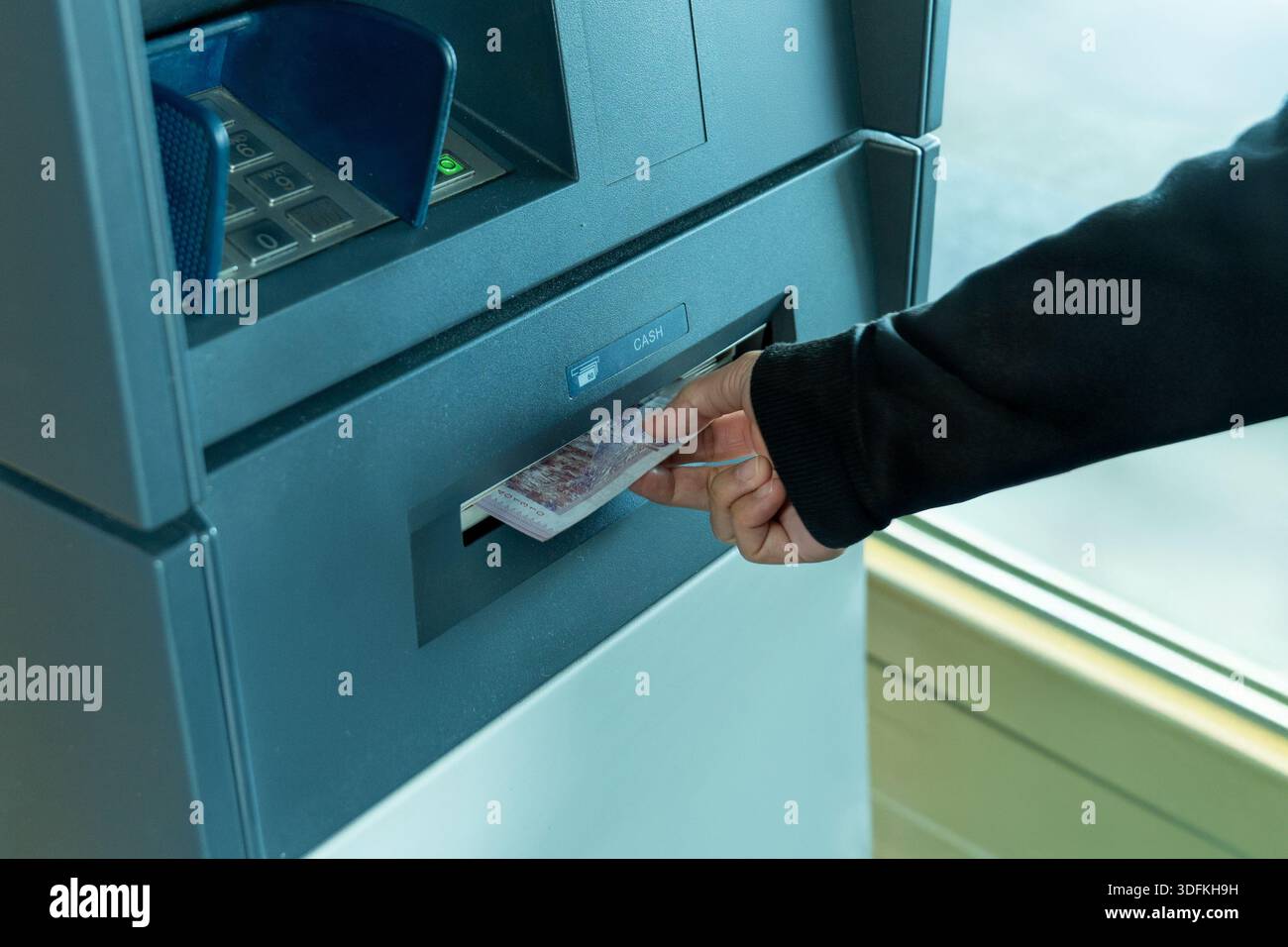Person, die Bargeld von einem Geldautomaten abhebt. Automatisierter Bankservice, persönliche Finanzen, modernes Finanztransaktionskonzept. Stockfoto