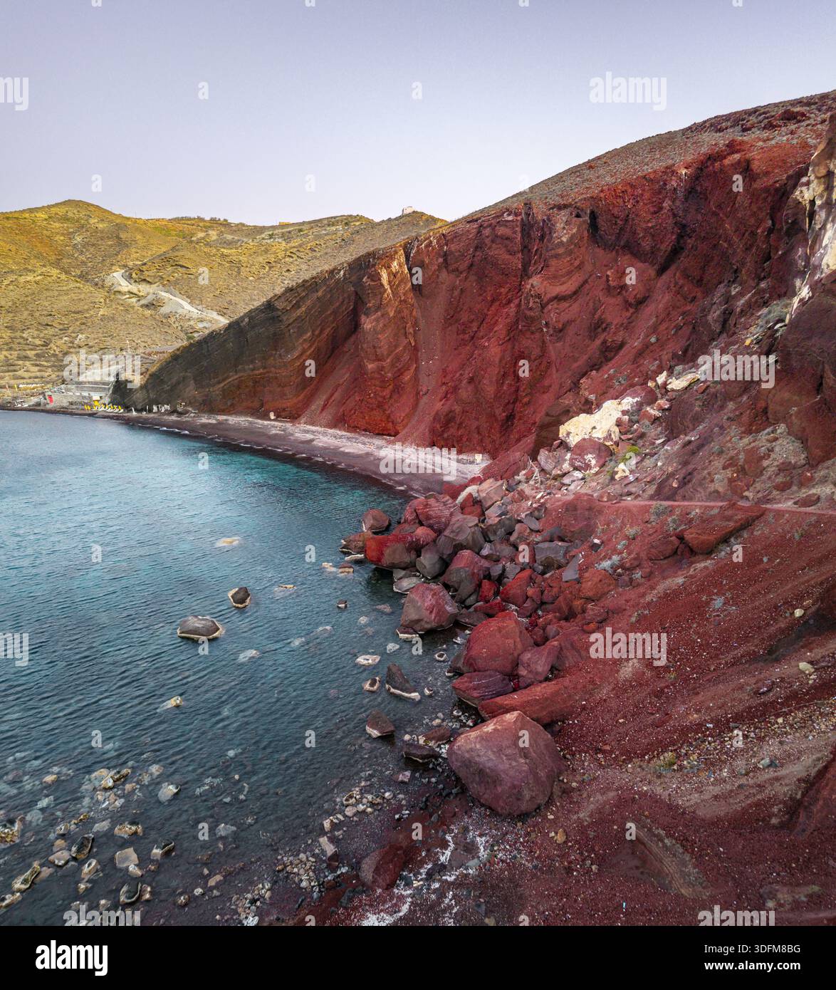 Aus der Vogelperspektive des beeindruckenden Kontrastes zwischen den tiefroten Klippen von Red Beach und der türkisfarbenen Ägäis, Santorin, Griechenland. Stockfoto