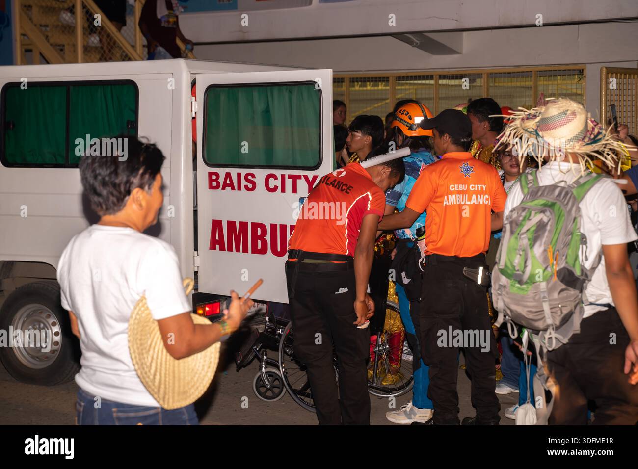 Emergency response, an ambulance from Bais City, Philippines, and personnel in orange shirts, one of whom has a "Cebu City Ambu" patch Stockfoto