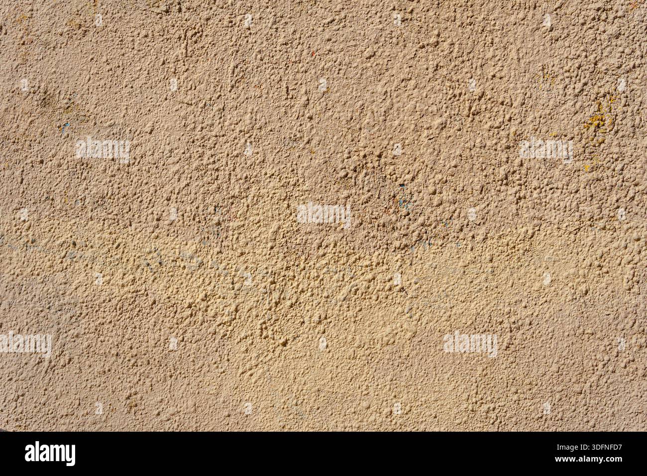 Eine gelbe Wand, bedeckt mit zahlreichen Gips- und Farbschichten. Die Schichten bilden kleine Unregelmäßigkeiten und Unebenheiten. Stockfoto