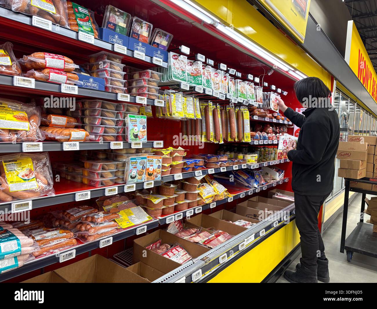 Mann, der die Produktpräsentation von Lebensmittelgeschäften mit Würsten, Aufschnitt und anderem verarbeitetem Fleisch organisiert. Stockfoto