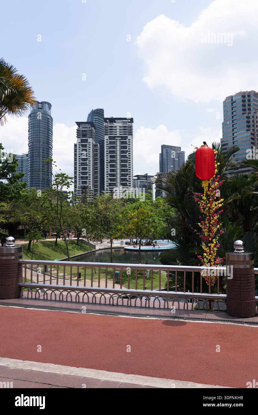 KLCC Park Bridge mit einer roten chinesischen Laterne, üppigen Bäumen und städtischen Wolkenkratzern im Hintergrund, Kuala Lumpur, Malaysia. Stockfoto