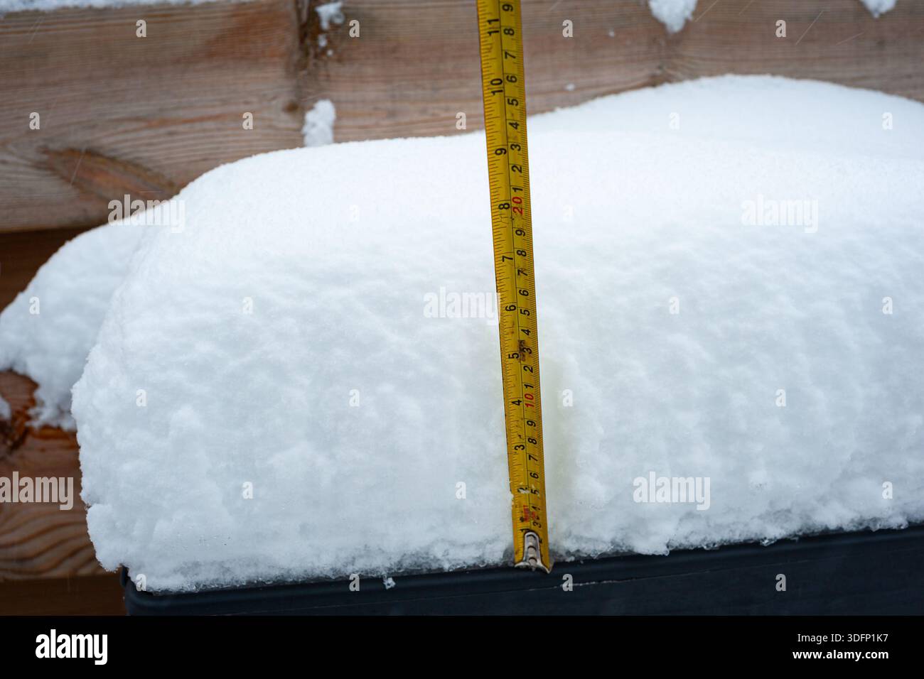 Dicke Schneeschicht auf einem Pflanzgefäß mit Lineal, das die Schneehöhe anzeigt Stockfoto