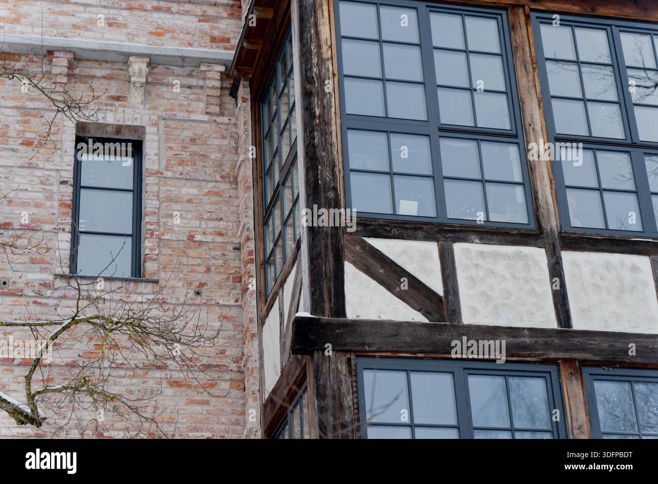 Traditionelles europäisches Gebäude mit Holzrahmenkonstruktion aus Ziegelwänden und großen Glasfenstern, die historische Architekturdetails veranschaulichen Stockfoto