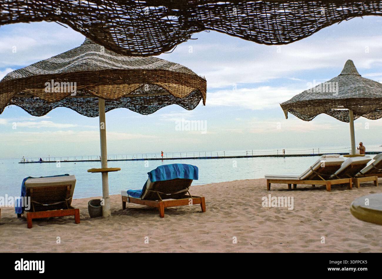 Leere Sonnenliegen unter Strohschirmen am Strand Sharm El Sheikh, Ägypten Stockfoto
