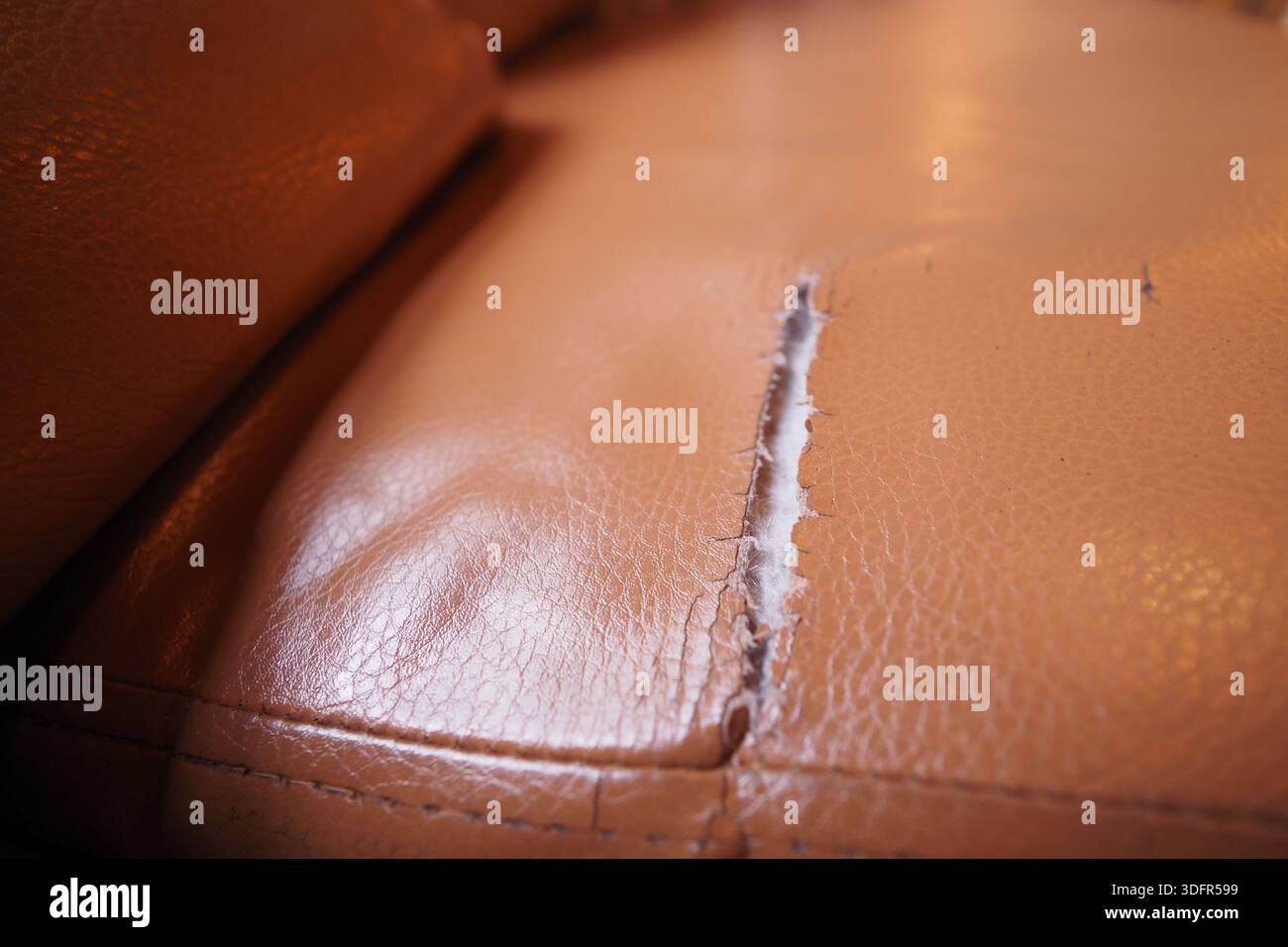 Das RIP auf dem Ledersofa zeigt Abnutzung im Laufe der Zeit Stockfoto