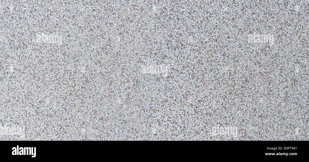 Graue Betonoberfläche mit vielen kleinen Granit- und Steinkieseln Stockfoto