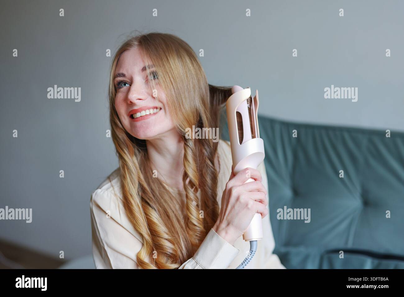 Attraktive Frau, die zu Hause mit entspanntem Lächeln und lässigem Outfit das Styling genießt Stockfoto