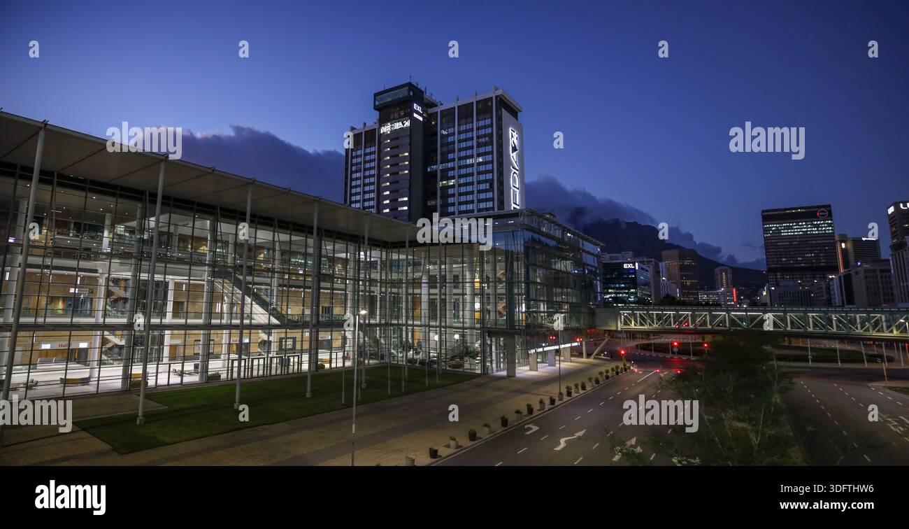 Kapstadt, Südafrika - 24. Dezember 2025: Blick auf die moderne Glasfassade des CTICC, die die Lichter der Stadt vor dem Hintergrund des Tafelbergs reflektiert Stockfoto