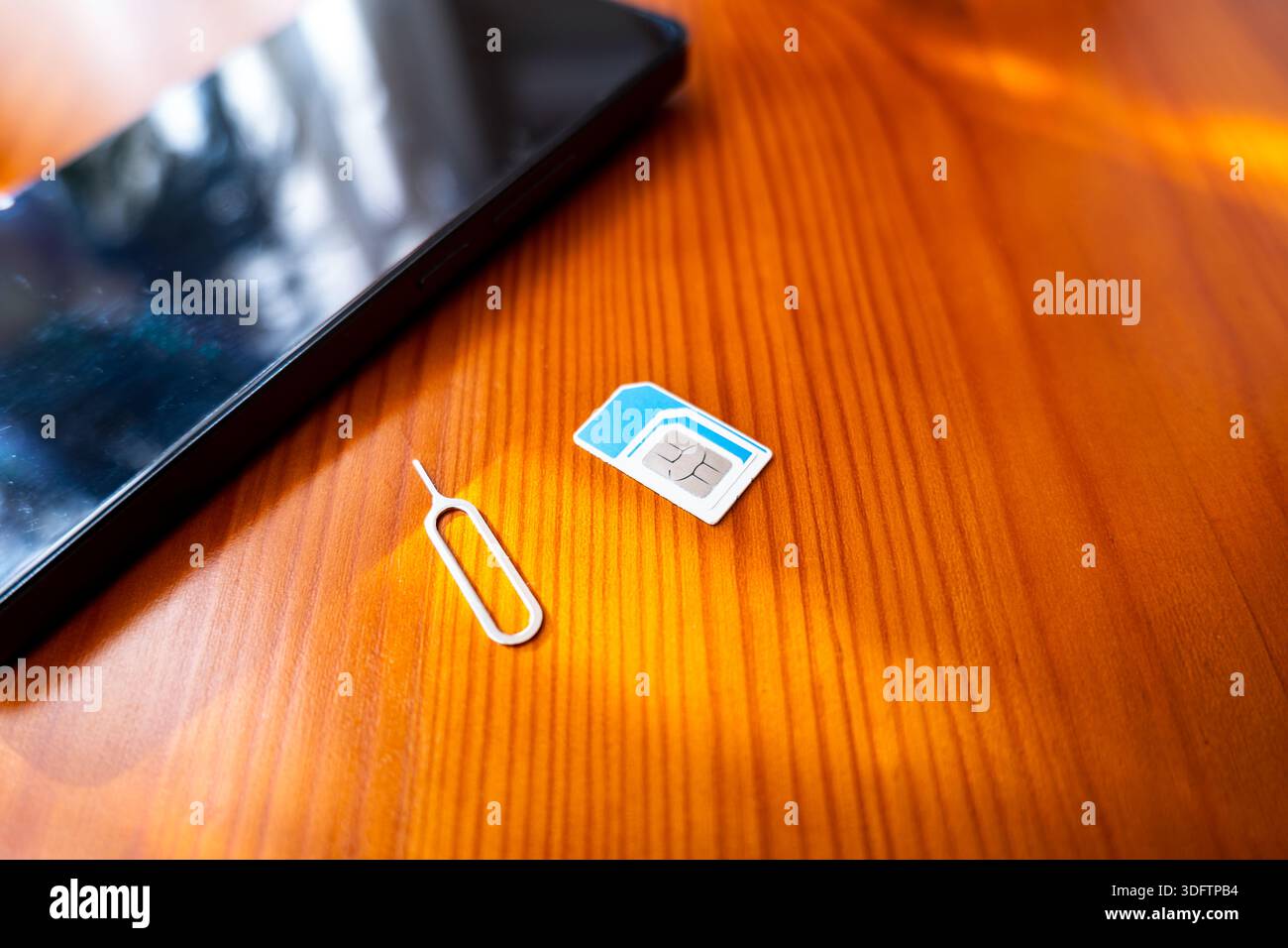 SIM-Karte und Auswurfstift neben dem Smartphone. Nano-sim-Karte auf dem Schreibtisch, Nahaufnahme Stockfoto