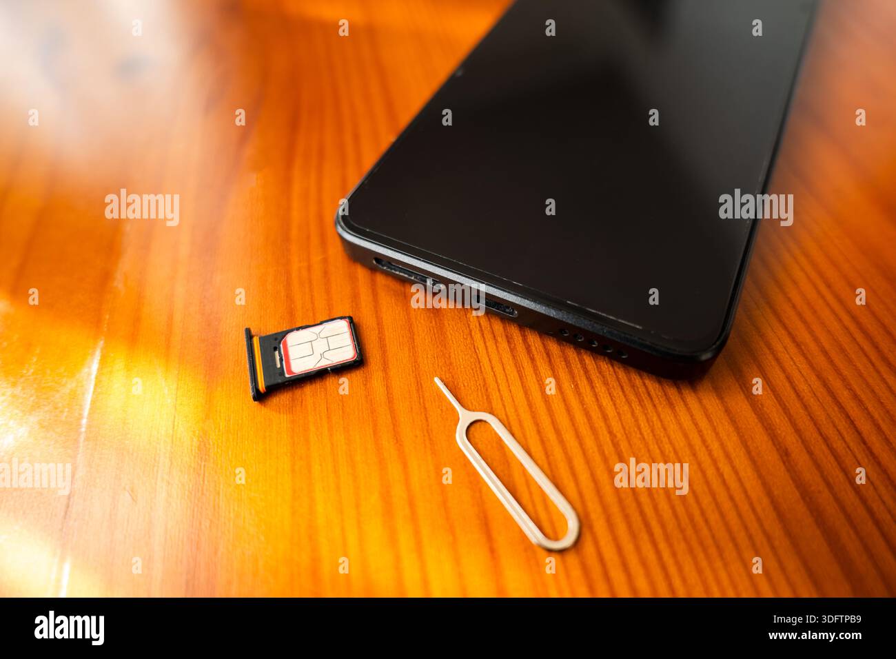 SIM-Karte und Auswurfstift neben dem Smartphone. Nano-sim-Karte auf dem Schreibtisch, Nahaufnahme Stockfoto