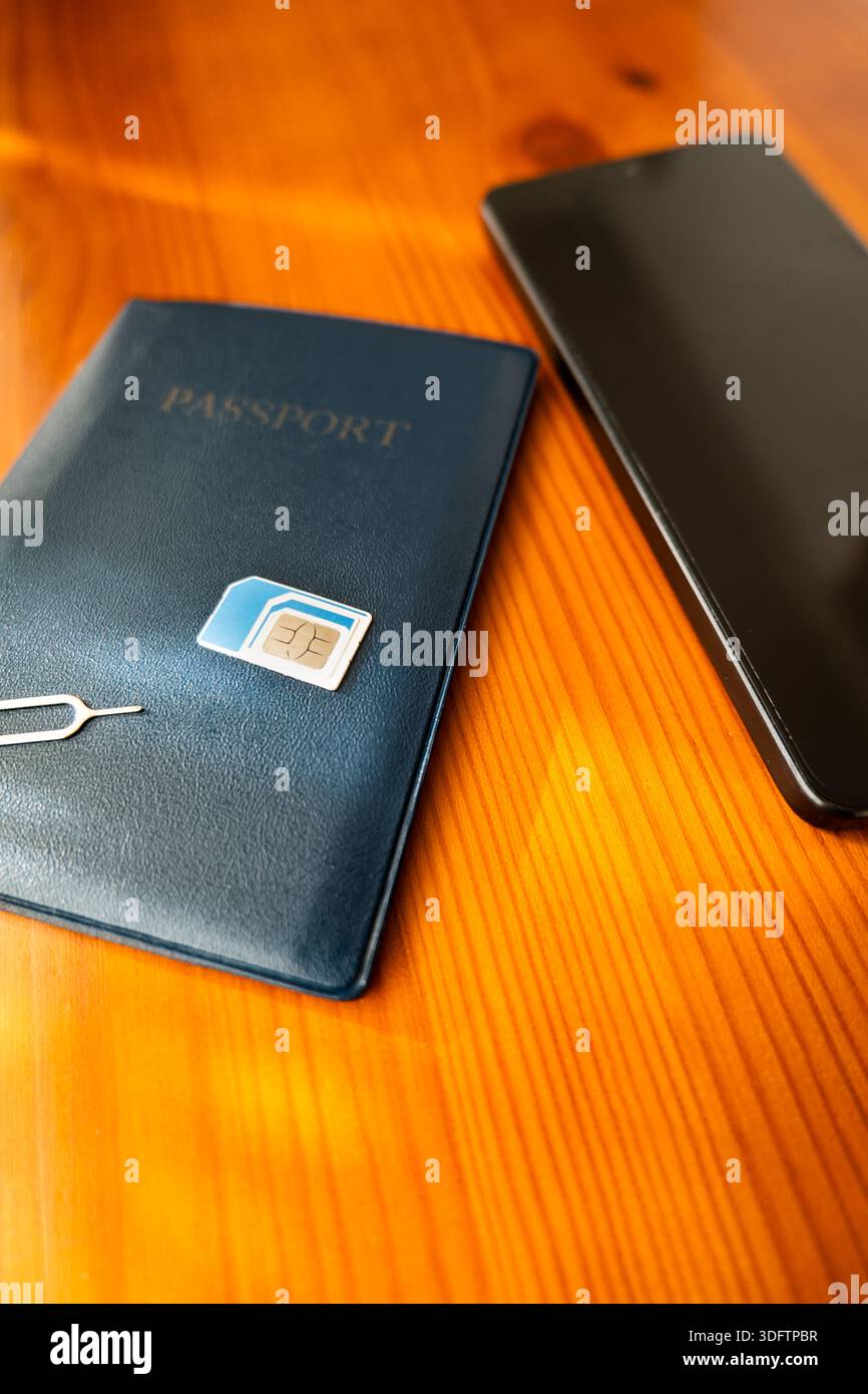 SIM-Karte und Reisepass neben dem Smartphone. sim-Karte auf Pass, Nahaufnahme Stockfoto