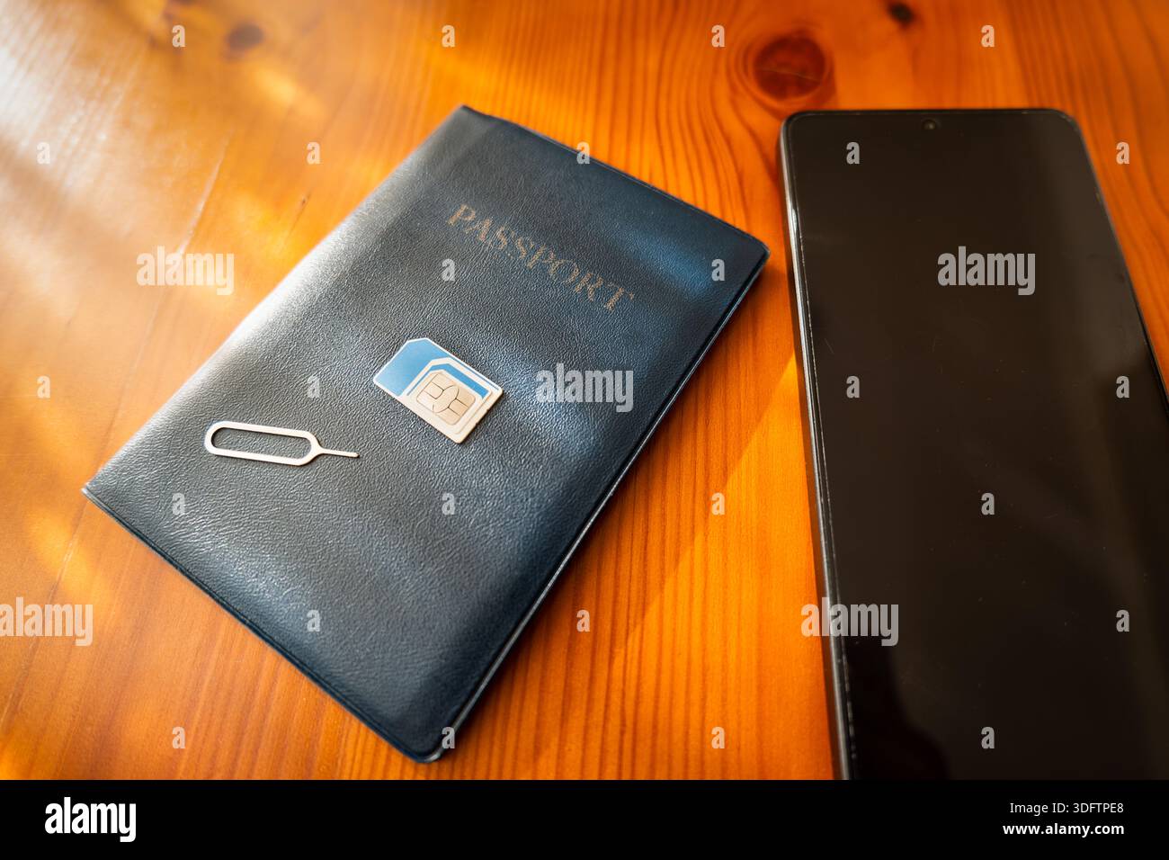SIM-Karte und Reisepass neben dem Smartphone. sim-Karte auf Pass, Nahaufnahme Stockfoto