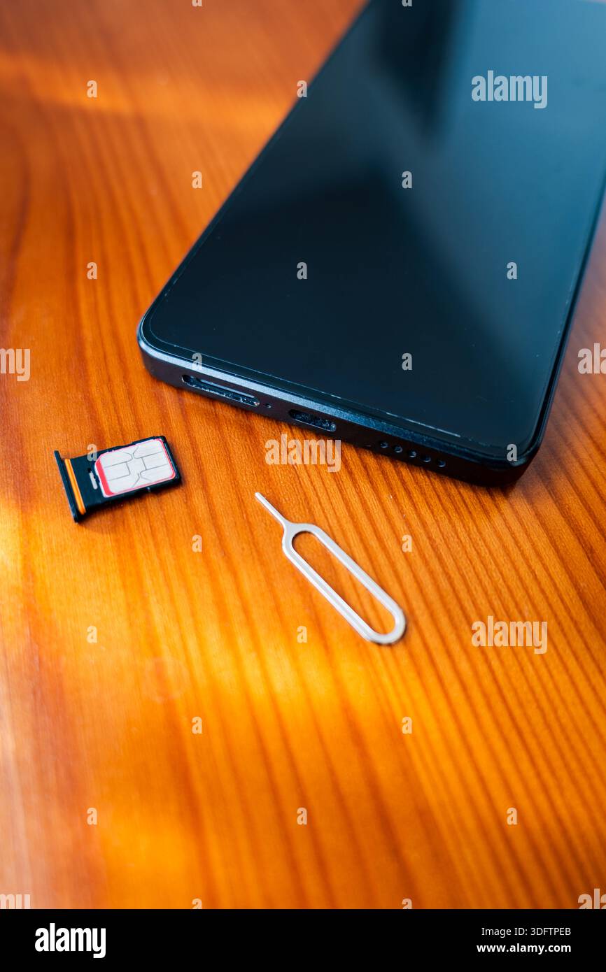 SIM-Karte und Auswurfstift neben dem Smartphone. Nano-sim-Karte auf dem Schreibtisch, Nahaufnahme Stockfoto