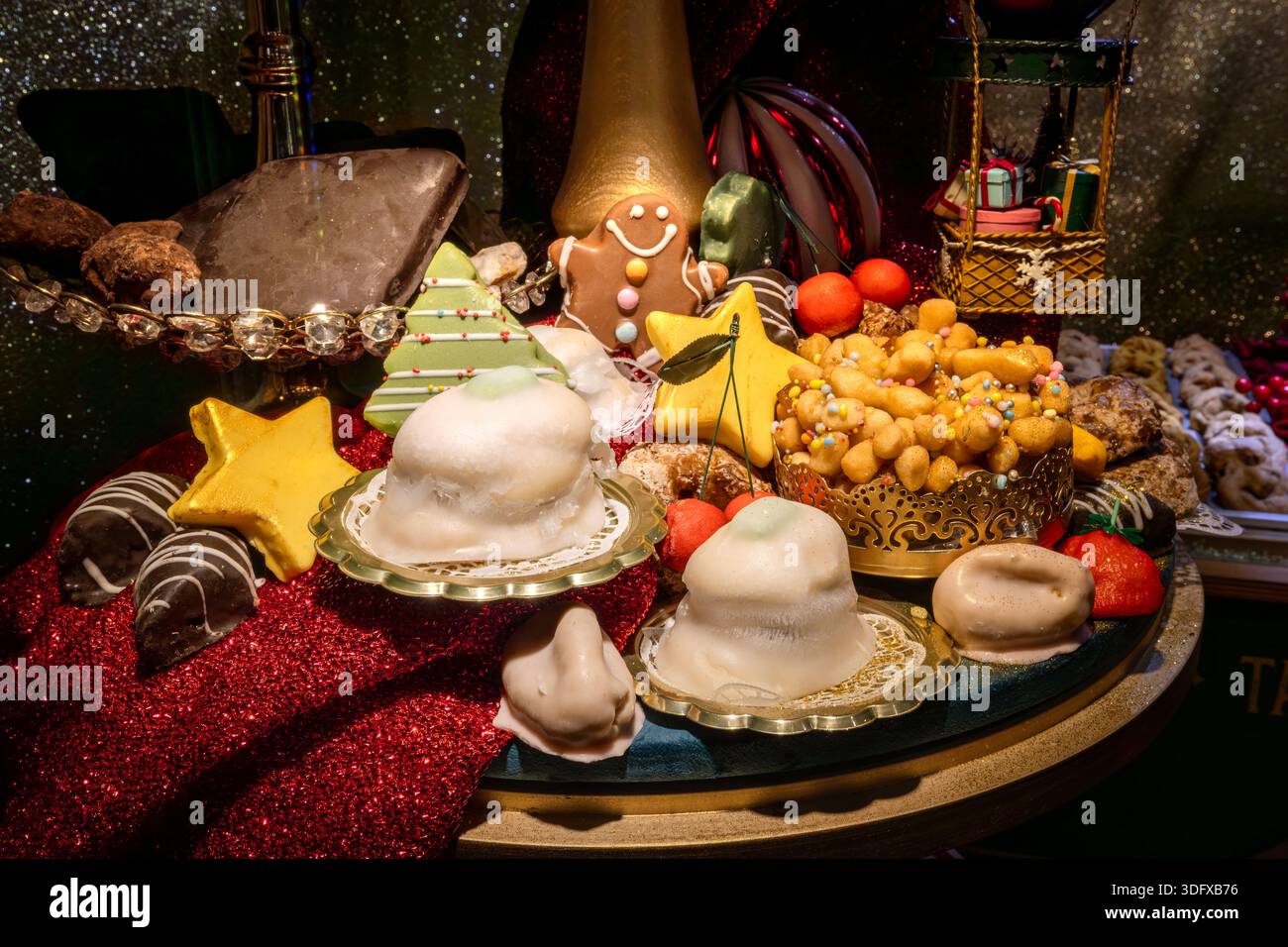 Ein reichhaltiger Tisch voller Weihnachtssüße: Lebkuchenmänner, weiß glasiertes Kassatin, Honig-Struffoli und Schokoladengerichte. Festliche Komposition mit Glitzer Stockfoto