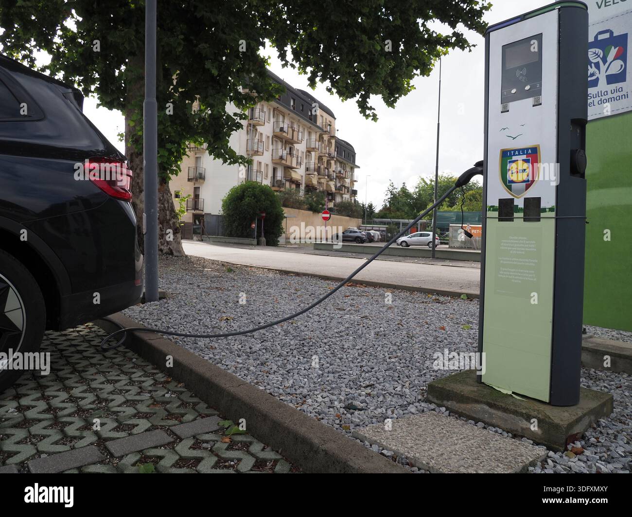 Ein Elektroauto lädt an einem modernen Stadtbahnhof mit elegantem Design auf, vor dem Hintergrund zeitgenössischer Gebäude und urbaner Landschaft Stockfoto